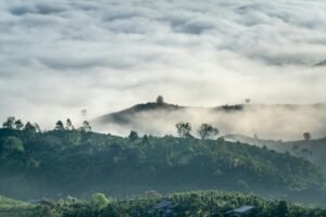A tranquil landscape of mist-covered hills with a dense cloud blanket above, capturing the essence of nature's serenity.